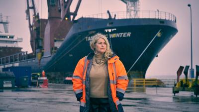 Dr Claire Pekcan standing in front of a ship in port.